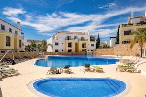 a swimming pool with chaise lounge chairs and a resort at Cosy Two Bedroom Apartment in Cabaços