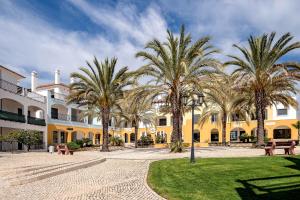 a group of palm trees in front of a building at Cosy Two Bedroom Apartment in Cabaços