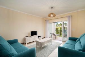 a living room with two blue couches and a tv at Cosy Two Bedroom Apartment in Cabaços