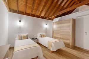 two beds in a room with white walls and wooden ceilings at Vista Valle in Mogán