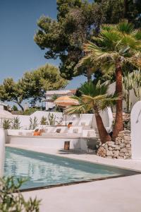 a swimming pool with palm trees next to a resort at The June Boutique in Benissa
