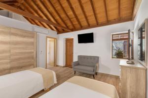 a bedroom with a bed and a chair and a television at Vista Valle in Mogán