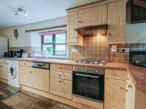a kitchen with wooden cabinets and a stove top oven at Cider House - near Lyme Regis in Axminster