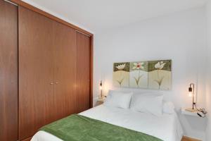 a bedroom with a white bed and a wooden cabinet at Atico Olia in Los Llanos de Aridane