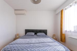 a bedroom with a bed with a blue comforter and a window at Cocooning proche plage in Fréjus