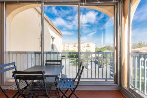 a balcony with a table and chairs and a window at Cocooning proche plage in Fréjus