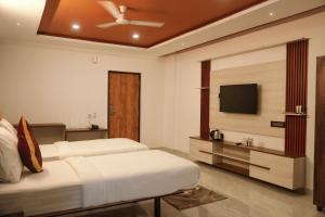 a bedroom with two beds and a flat screen tv at Hemagiri Palace in Avati