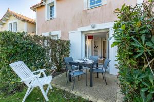 a patio with a table and chairs in front of a house at Maison Village Port-Bourgenay in Saint-Hilaire-de-Talmont
