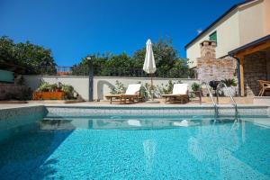 a swimming pool with an umbrella next to a house at Heritage Holiday Home Rafica 365 Wellness Retreat in Božava