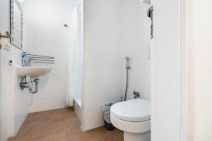 a white bathroom with a toilet and a sink at Aldars Urban Trio Suite No.5 in Munich +16 photos