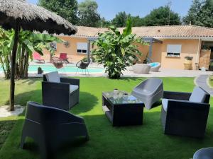 a patio with chairs and a table on grass at Chambre d'hôtes Le Nid'zen in Le Nizan