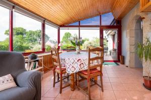 a dining room with a table and chairs and windows at Gite Refuge du Blavet 2 étoiles in Saint-Barthélemy