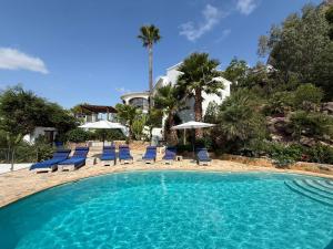 a swimming pool with blue chairs and umbrellas at Caroix in Jávea
