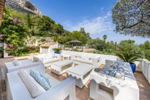 a patio with white wicker chairs and tables and trees at Caroix in Jávea