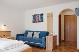 a blue couch in a room with a bed at Ciasa Willy App Lavarella in La Villa