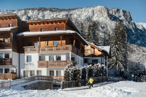 a man is skiing in front of a building in the snow at Ciasa Willy App Lavarella in La Villa +18 photos