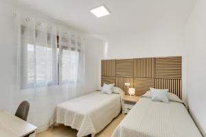a white bedroom with two beds and a desk at Casas de Vacaciones Ibaiale in Cazadores