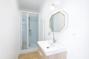 a white bathroom with a sink and a mirror at Chambres d'hôtes pleine nature in Plougonven