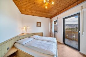 a bedroom with a bed and a large window at Residence Kronstein - Fewo 9 in Tesimo