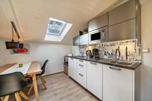 a kitchen with white cabinets and a wooden table at Residence Kronstein - Fewo 9 in Tesimo