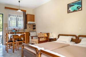 a bedroom with two beds and a kitchen with a table at Daratos studio 2 in Kefallonia