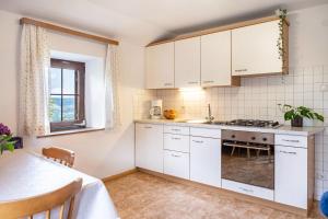 a kitchen with white cabinets and a table at Stablerhof Apt Löwenzahn in Cornedo all'Isarco