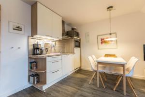 a kitchen with a table and white cabinets at Ferienwohnung Ulstrup in Böhl +14 photos