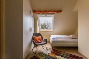 a bedroom with a chair and a bed and a window at Ferienwohnung Ulstrup in Böhl