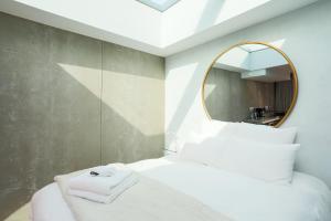 a bedroom with a white bed with a mirror at Ecolodge à 300m de la plage in Pléneuf-Val-André