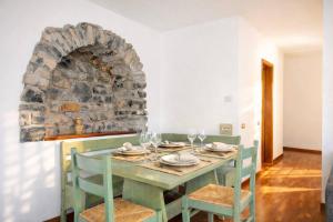 a dining room with a table and a stone wall at Emilia's Lakeview Terrace in Brienno