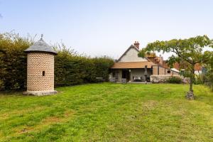 a house with a brick chimney in a yard at Gîte des Aulneaux in Fresnes