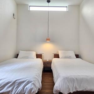 two beds in a room with white sheets at Kuro in Hakodate