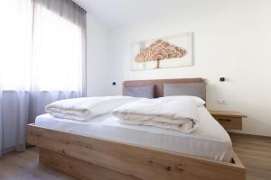 a bedroom with a wooden bed with white sheets at Kleon 1 in Rifiano