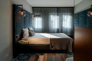 a bedroom with a bed and a table and windows at Hotel Derlon in Maastricht