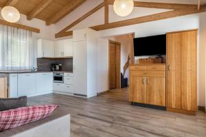 a kitchen with white cabinets and a flat screen tv at Apt Gamsstube in Maranza