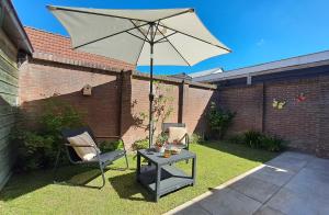 a patio with a table and an umbrella and a chair at Camino in Vrouwenpolder