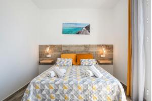 a bedroom with a bed with an orange and gray comforter at Casa Bombón in Vejer de la Frontera +18 photos