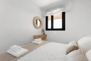 a white bedroom with a bed and a mirror at Adhara 053 in Torre del Mar +12 photos