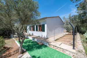 a house with a green lawn in front of it at Es Jaç in Cala Llombards