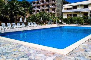 a large blue swimming pool with chairs and a building at Mono Le Lecce 25 b in Capoliveri