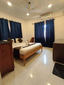 a bedroom with two beds and blue curtains at 1 Bhk apartment kyle garden baga beech in Baga