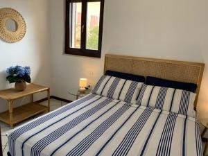 a bed with a blue and white striped comforter in a bedroom at Villino Le Ortensie in Stintino
