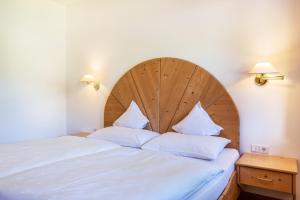 a bed with a large wooden headboard and two pillows at Sabina Dolomites Joch in Alpe di Siusi