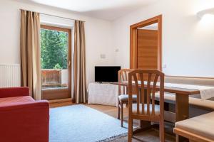 a living room with a table and a couch and a television at Sabina Dolomites Joch in Alpe di Siusi