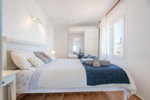a white bedroom with a large bed and a window at Wonderful in Can Picafort
