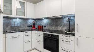 a kitchen with white cabinets and a black dishwasher at Fewo-Gottmadingen in Gottmadingen