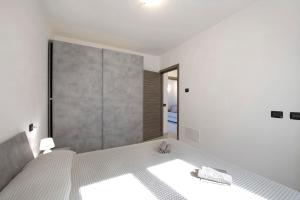 a white bedroom with a bed and a large mirror at Appartamento 7 Il Tornante in Nesso +18 photos