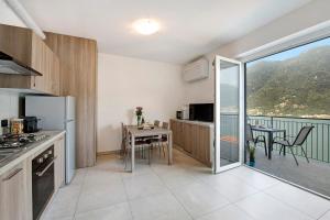 a kitchen with a table and a balcony with a view at Appartamento 7 Il Tornante in Nesso