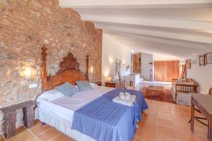 a bedroom with a bed and a stone wall at Sa Cabana Vella Fornalutx in Fornalutx
