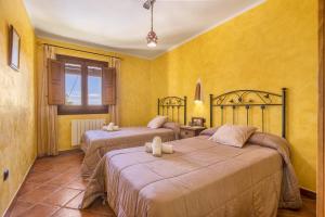 two beds in a room with yellow walls at Cortijo Jiménez in Pitres +21 photos